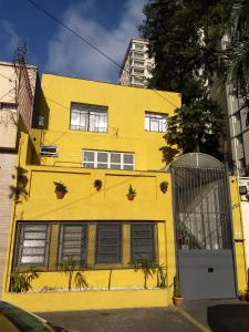 圣保罗Hospedaria Cambuci Unidade Ipiranga的一座黄色的建筑,前面有植物