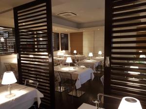 斯泰扎诺佩加索艾若波特美居酒店的餐厅配有白色的桌椅和灯光