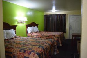 克莱尔莫尔克莱尔莫尔汽车旅馆的一间酒店客房,设有两张床和绿色的墙壁
