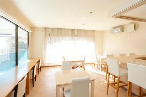 甲府索诺马马酒店的用餐室配有桌子和白色椅子