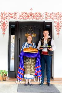 PonoareleConacu´ Boierului的身着传统服装的男人和女人站在房子前面