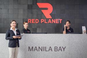 马尼拉Red Planet Manila Bay的三个女人站在红色星球码头标志后面