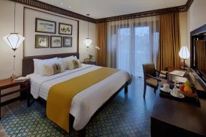 会安Little Hoi An . A Boutique Hotel & Spa的酒店客房设有一张大床和一张书桌。