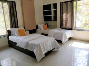浦那Bauhinia的一间卧室配有两张带白色床单和橙色枕头的床。