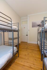 蒙特卡罗埃斯托里尔Change The World Hostels - Cascais - Estoril的客房设有三张双层床,铺有木地板。
