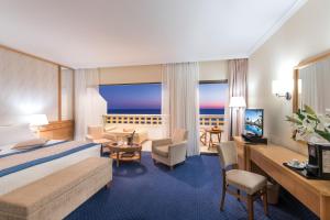 帕福斯康斯坦丁诺雅典娜皇家海滩酒店的酒店客房,配有一张床、一张桌子和椅子