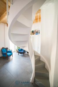 塔兰托Bed & breakfast La Nassa的客厅里白色的螺旋楼梯,配有蓝色的椅子