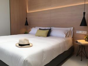 毕尔巴鄂Inside Bilbao Apartments的一张白色的床,上面有帽子