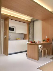 毕尔巴鄂Inside Bilbao Apartments的厨房配有白色橱柜和木桌