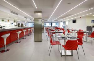马德里优斯达赛特酒店的一间设有红色桌椅的餐厅和一间酒吧