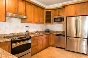 苏莎亚Luxury Oceanview Condo 2 BR/2.5 BA的厨房配有木制橱柜和不锈钢用具