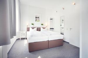蒙塔鲍尔莱恩古斯酒店的一间白色卧室,配有一张床和两面镜子