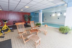布鲁克斯瓦拉那Hotell Bruksvallsliden的一间带两张木椅的房间和一个游泳池