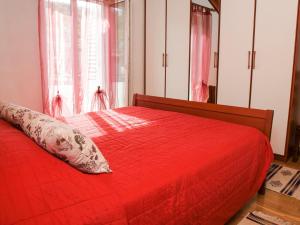 波斯蒂拉Lozna Apartment的红色的床,配有红色的棉被和枕头