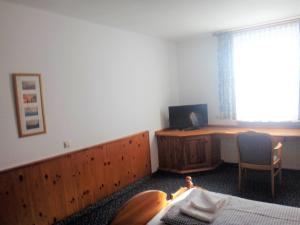 林道灵多尔巴登海景酒店的一间卧室配有一张床、一张书桌和一个窗户。