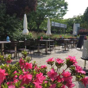 塞尔吉塞日圣克里斯多夫钟楼酒店的庭院配有桌椅和粉红色的鲜花