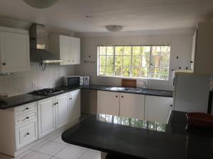 约翰内斯堡Summerview Guest Lodge的厨房配有白色橱柜和窗户。