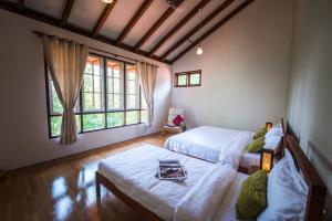 彭亨Rest Pause Rainforest Retreat的一间卧室设有两张床和两个窗户。