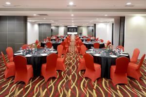 帕朗卡拉亚Hotel Neo Palma Palangkaraya by ASTON的一间会议室,配有桌子和红色椅子