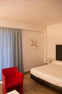 克雷马公园宅邸酒店的一间卧室配有一张床和一张红色椅子