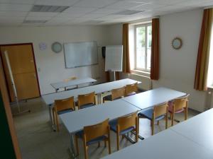 蒂宾根蒂宾根青年旅舍的一个带桌椅的教室和一个黑板