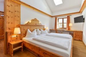 罗森海姆朱姆艾丁格维斯布劳兰德加斯特霍夫酒店的一间卧室配有一张大床和木制床头板