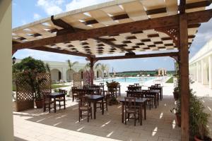切萨雷奥港Agri Hotel Conte Salentino的一个带桌椅的户外庭院和一个游泳池