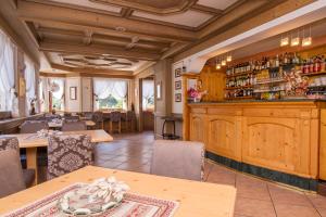 费拉迪普利米罗Hotel Al Prato的餐厅设有酒吧,配有木柜和桌子