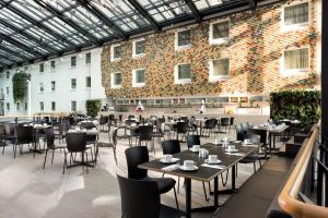 柏林柏林埃斯特酒店的一间带桌椅的餐厅以及一座大型砖墙
