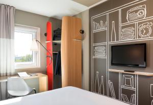 曼彻斯特宜必思曼切斯特圣切尔西酒店的一间卧室配有一张床,墙上挂着绘画。