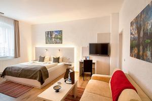 吕本瑙卡托非加斯特豪斯尼德宾希酒店的一间卧室配有一张床、一张桌子和一张沙发