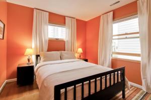 波特兰多伊尔洛夫乔伊酒店的一间卧室拥有橙色的墙壁,设有一张床和两个窗户。