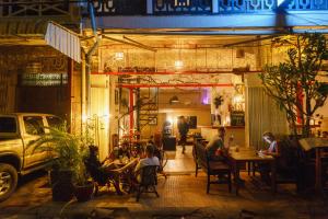 马德望Pomme Hostel Restaurant & Bar - Private Sleeping Cabins的一群人晚上坐在餐馆里