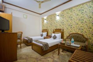 新德里日星大酒店 的一间酒店客房,设有两张床和电视