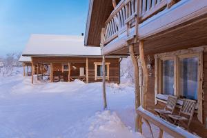 基尔匹斯扎我维Saivaara Cottages的雪地小木屋,前面设有两把椅子