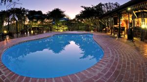 赫卢赫卢韦Isinkwe Bush Camp的一座大型蓝色游泳池,设有砖砌庭院