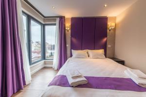 布加勒斯特The Embassy Nord的一间卧室配有一张大床和紫色床头板