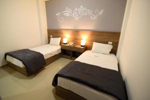 齐克拉约Hotel Escala的一间卧室配有两张床和一张带两盏灯的桌子。