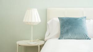 瓦伦西亚圣维森特HQ客房公寓的一张带蓝色枕头的床和一张桌子上的灯