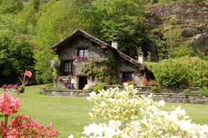 巴切诺Chalet La Baita的庭院里一座花卉的小石头房子