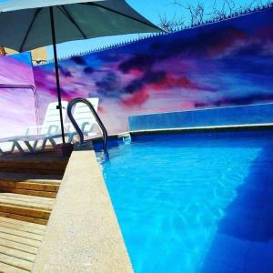 伊基克Aotea Hostel Iquique的一个带遮阳伞和壁画的游泳池