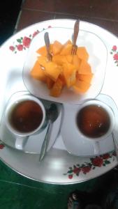 BajawaHotel Edelweis 2 Bajawa的盘子,盘子上放着两杯咖啡和一盘水果