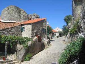 蒙桑图Casa da Gruta (Cave House)的街道边有大石头的石头房子