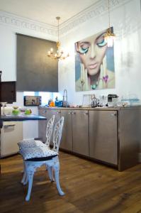 莱昂紫狗套房公寓的厨房配有两把白色椅子和墙上的绘画作品