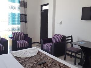 亭可马里Trinco Lagoon的酒店客房配有一张床、两把椅子和一张桌子