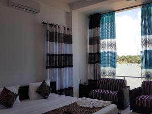 亭可马里Trinco Lagoon的一间卧室配有一张床、一张沙发和一个窗口