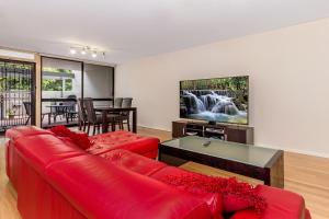 珀斯城市花园公寓的客厅配有红色沙发和电视