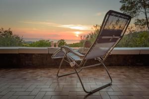 蓬塔阿拉Punta Ala Luxury Villa的坐在庭院的椅子上,背靠着日落