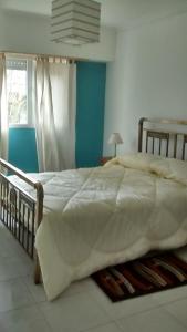 坦迪尔Departamentos R y R Azcuénaga的卧室配有一张带白色棉被的大床