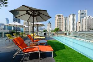 曼谷曼谷德特尔酒店的一座建筑屋顶上带椅子和遮阳伞的游泳池